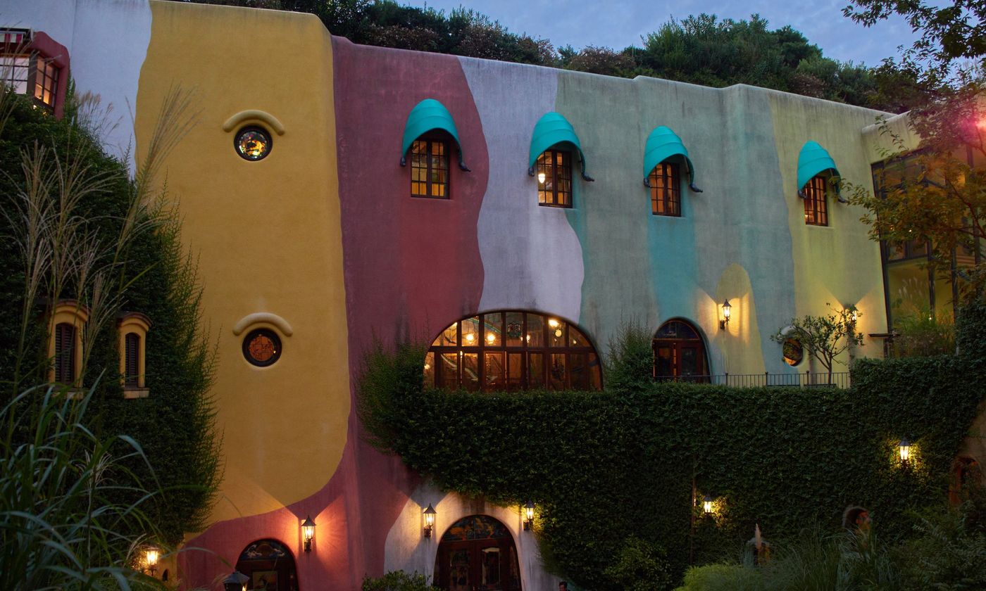 The multicoloured facade of the Ghibli Museum in Mitaka at dusk, with lit windows under a curved roofline